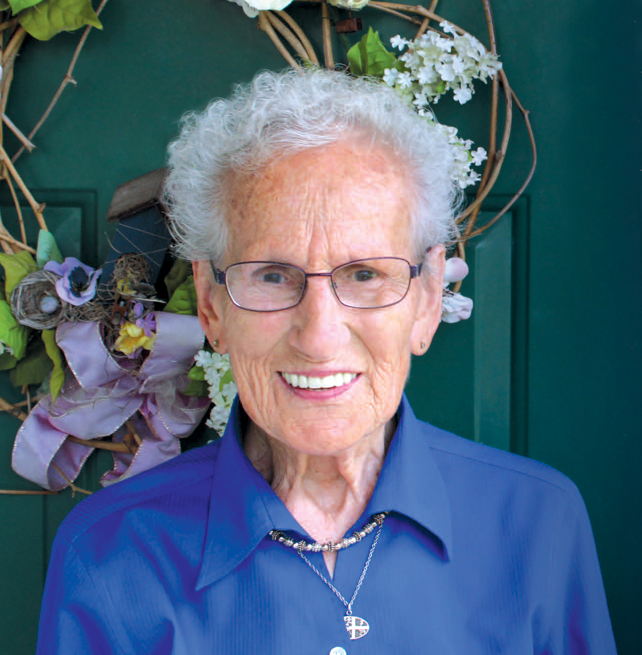 Sr. Dora in a blue shirt, wearing glasses, and smiling.