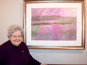 Sister Carla smiling with one of her original artworks.