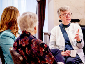 Three women seated, engaged in conversation.